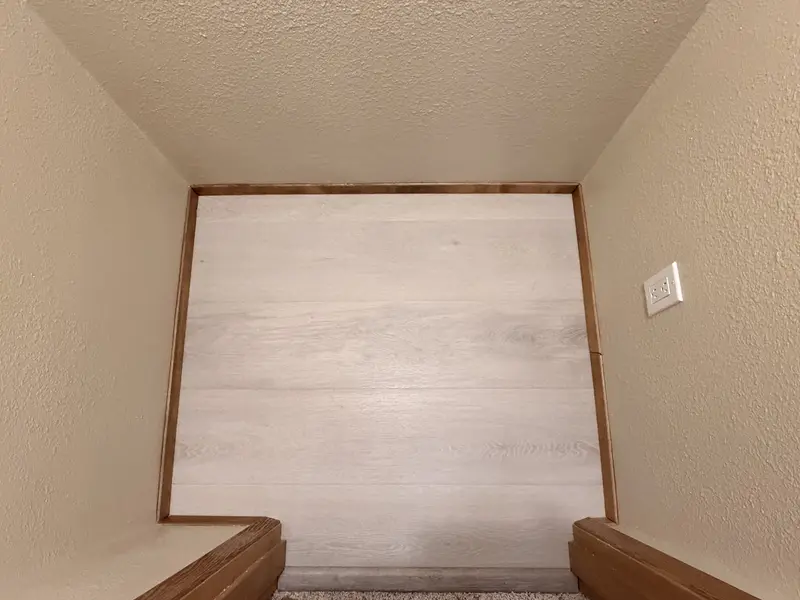 New light plank flooring with wood trim inside a closet