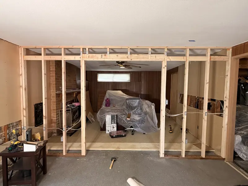New wall framed across an open room, with a wide rough opening