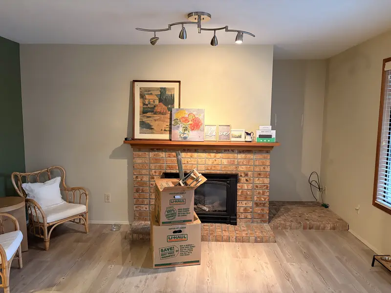 Living room with a brick fireplace and an empty alcove before repairs