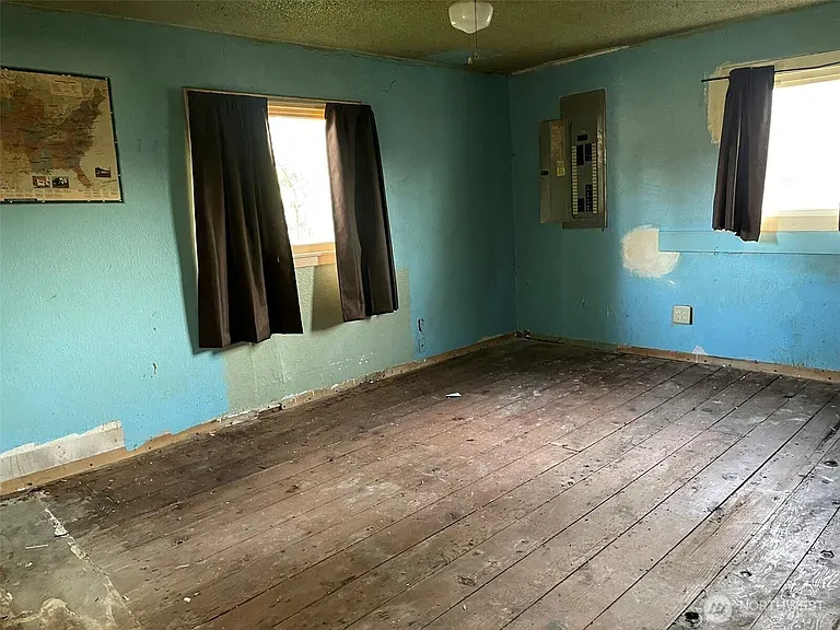 Emptied bedroom with blue walls, dark curtains and bare plank floors