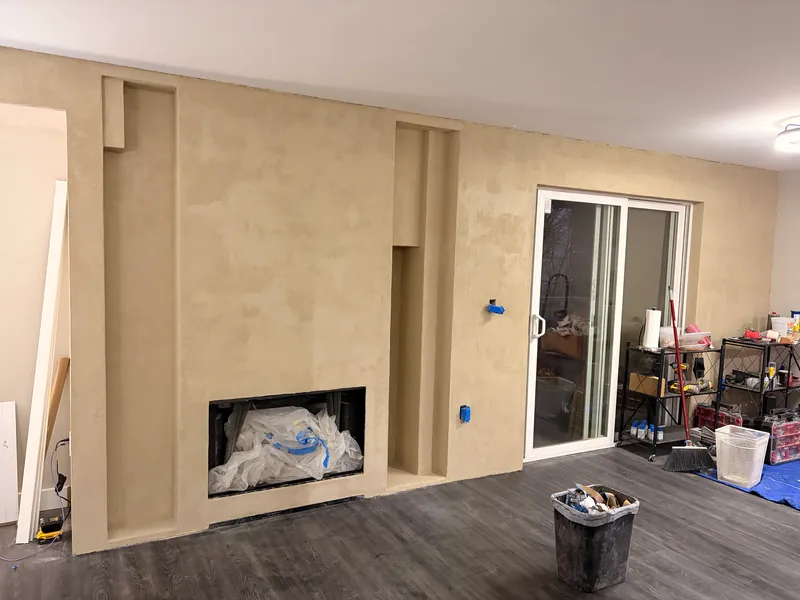 Fireplace and kitchen wall mid-way through a microcement finish