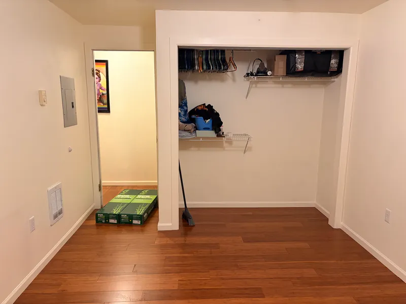 Empty room with a closet and new plank flooring running into the hallway