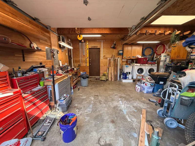 Inside the heated workshop with red tool chests, workbenches and stored materials